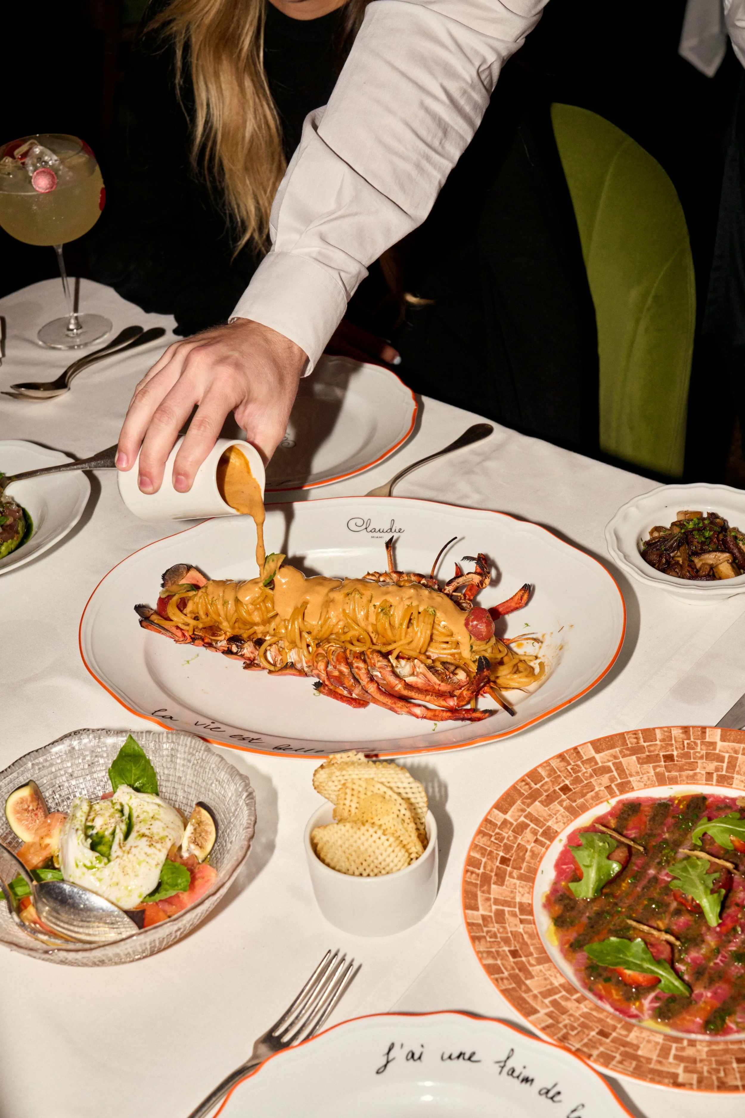 Claudie's lobster pasta dish, with the sauce being poured over by the server.
