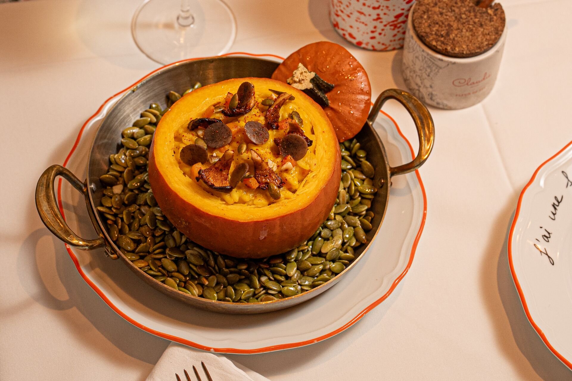 Roasted pumpkin stuffed with creamy filling, mushrooms, nuts, and seeds, served in a skillet.