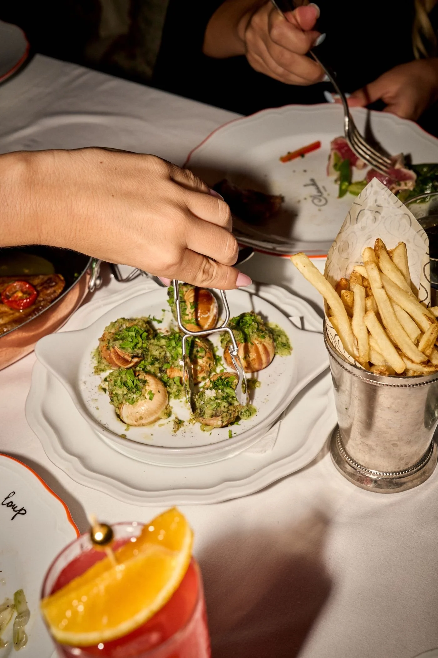 A woman taking one of the escargot served at CLAUDIE.