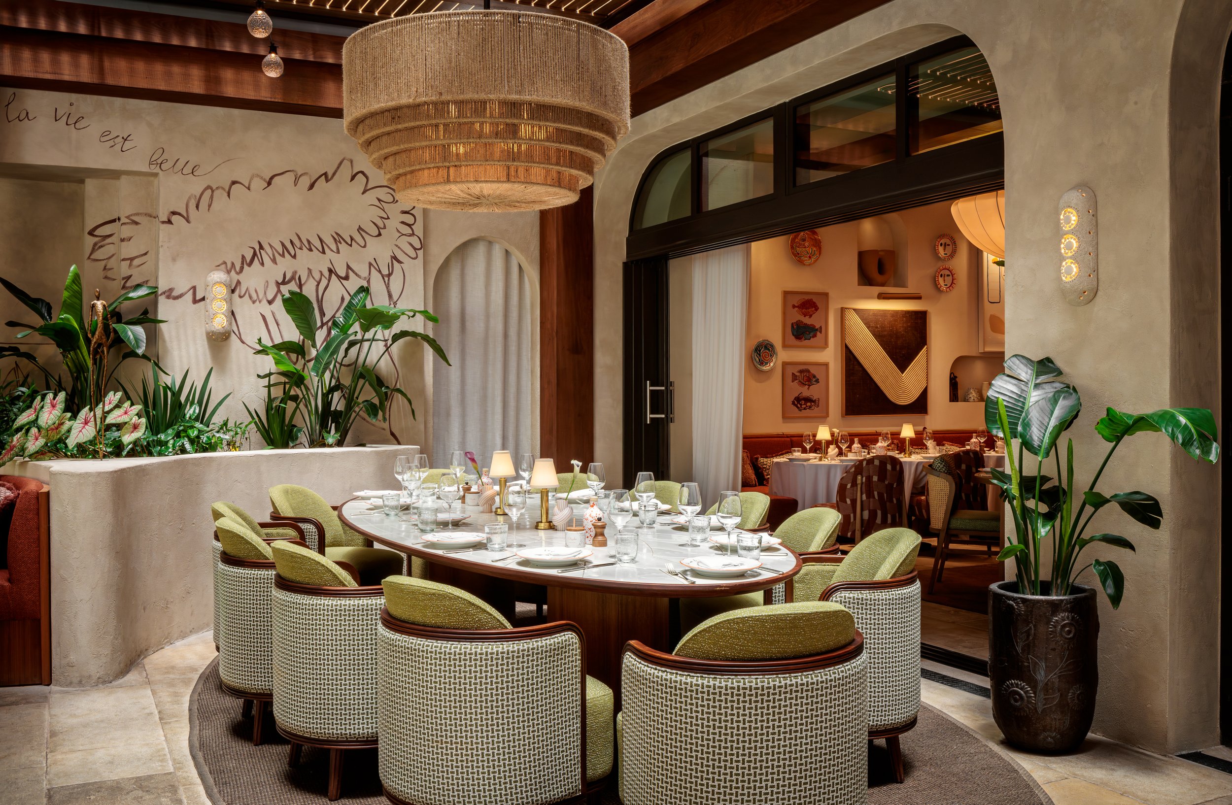 CLAUDIE's dining table for a big party, with green comfortable seats around an oval table.