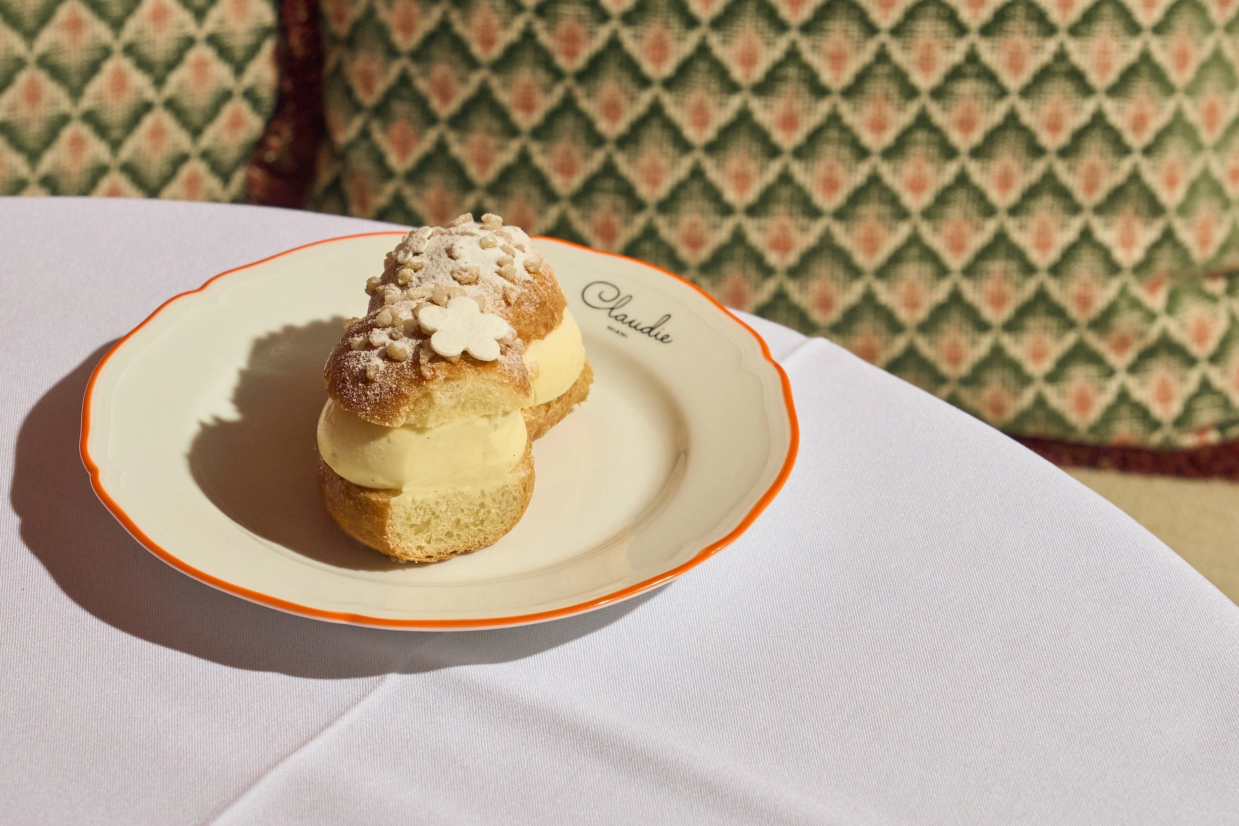 A tropezienne Tarte dessert garnished with powdered sugar on a table at CLAUDIE restaurant.