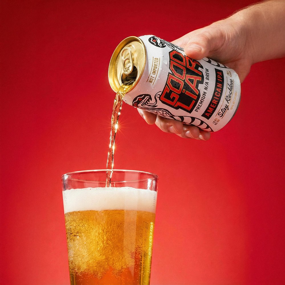 A hand pouring a can of Coors Light beer into a glass against a red background.