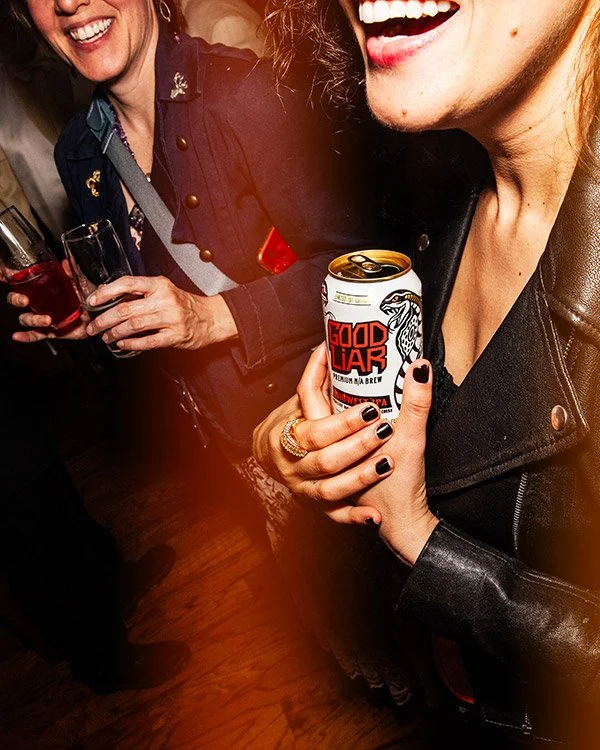 People enjoying drinks at a social gathering, one person holding a can with the label 'Good Liar' and others holding glasses of beverages, smiling and laughing.