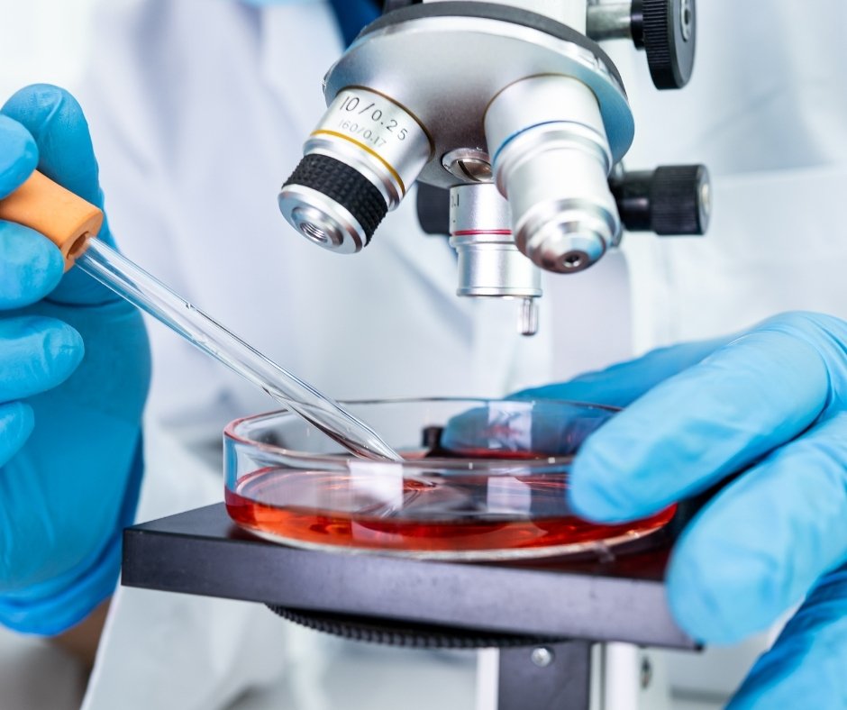 Gloved hands use a pipette to place a blood sample into a dish under a microscope | Blue Lotus Telepsychiatry Services, Inc.