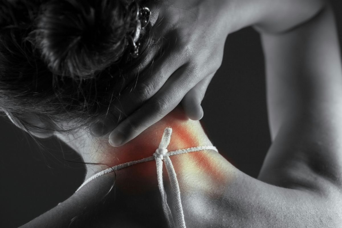 A black and white close-up of a hand touching the back of a neck, with a red-highlighted area marking tension and a cord tied around it | Blue Lotus Telepsychiatry