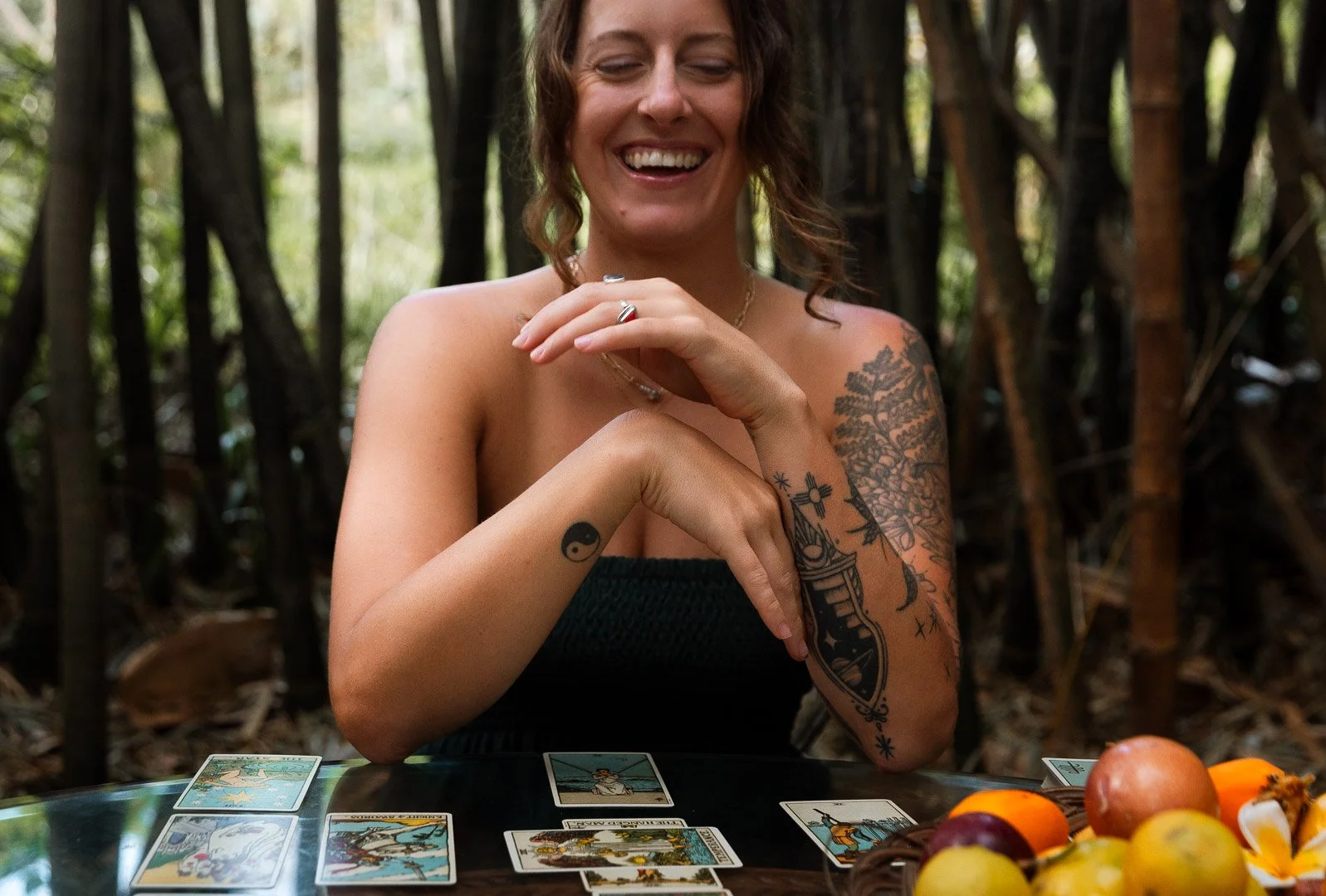 A professional astrologer laughing in nature with a tarot card spread 