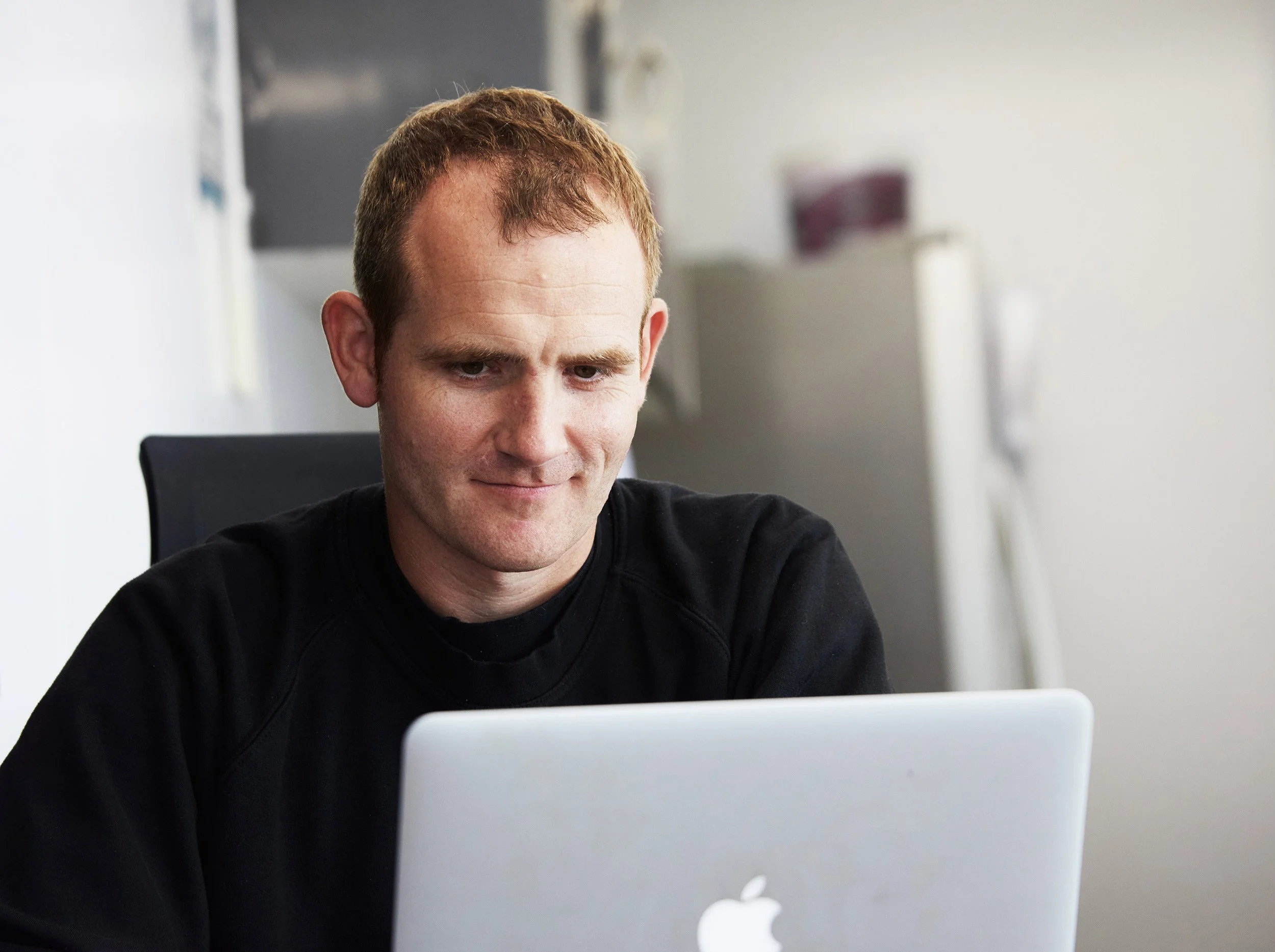 Man with short light brown hair working on a laptop in an office