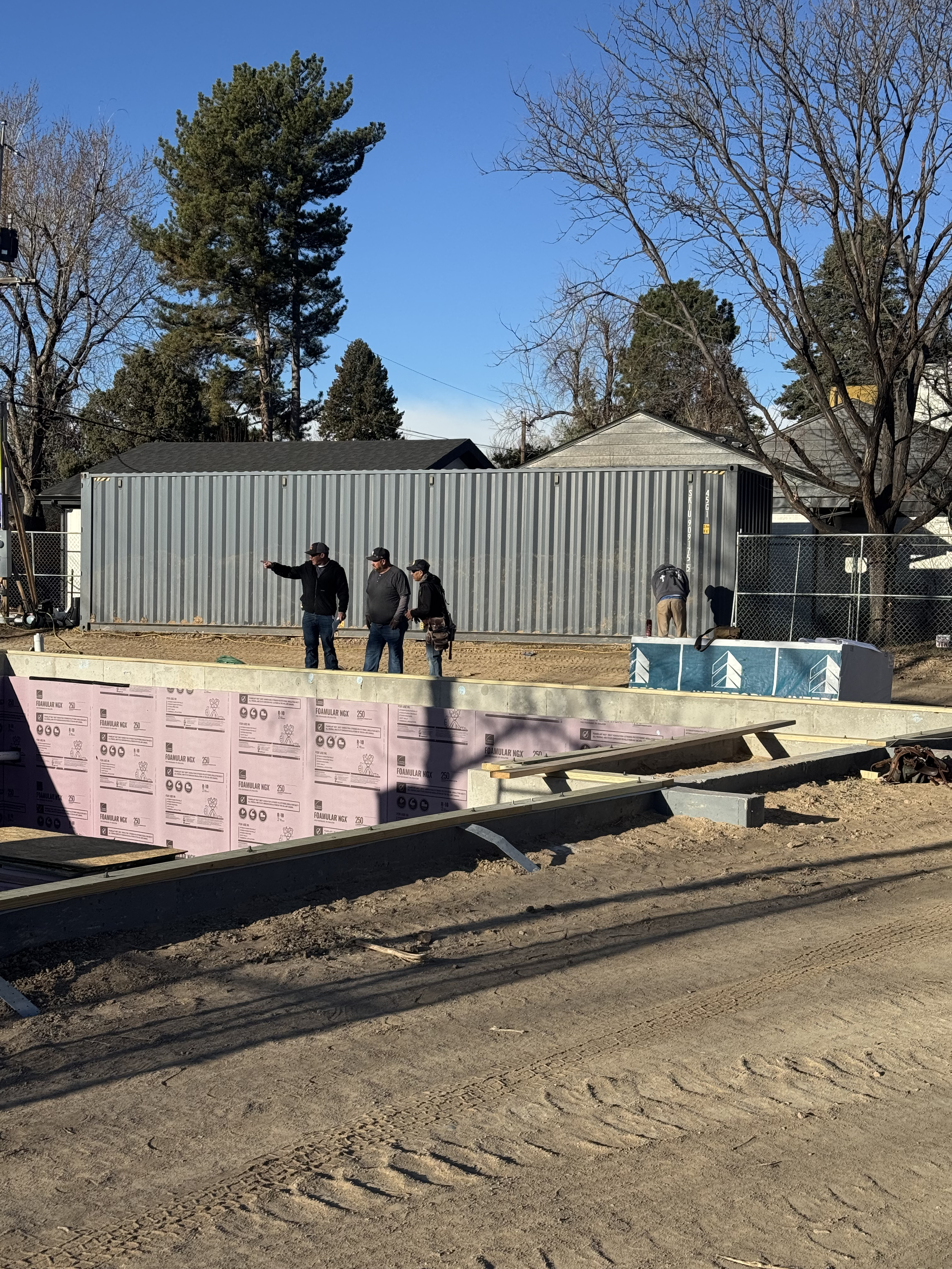 The Elizabeth Victorian-style home addition. Mid-project construction site with three men discussing in front of a large gray metal container