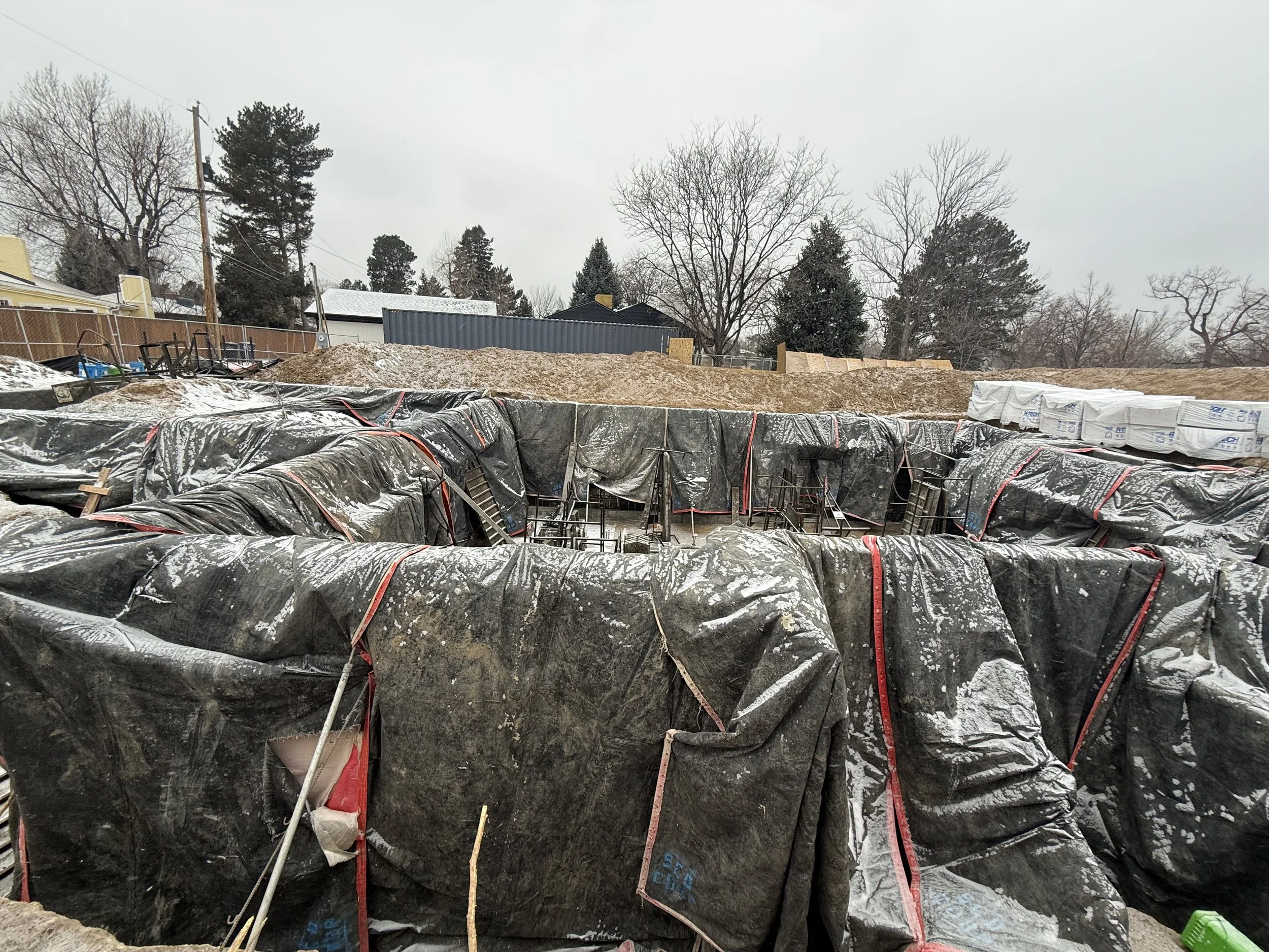 The Elizabeth Victorian-style home addition. Mid-project construction site with below-ground foundation being prepared.