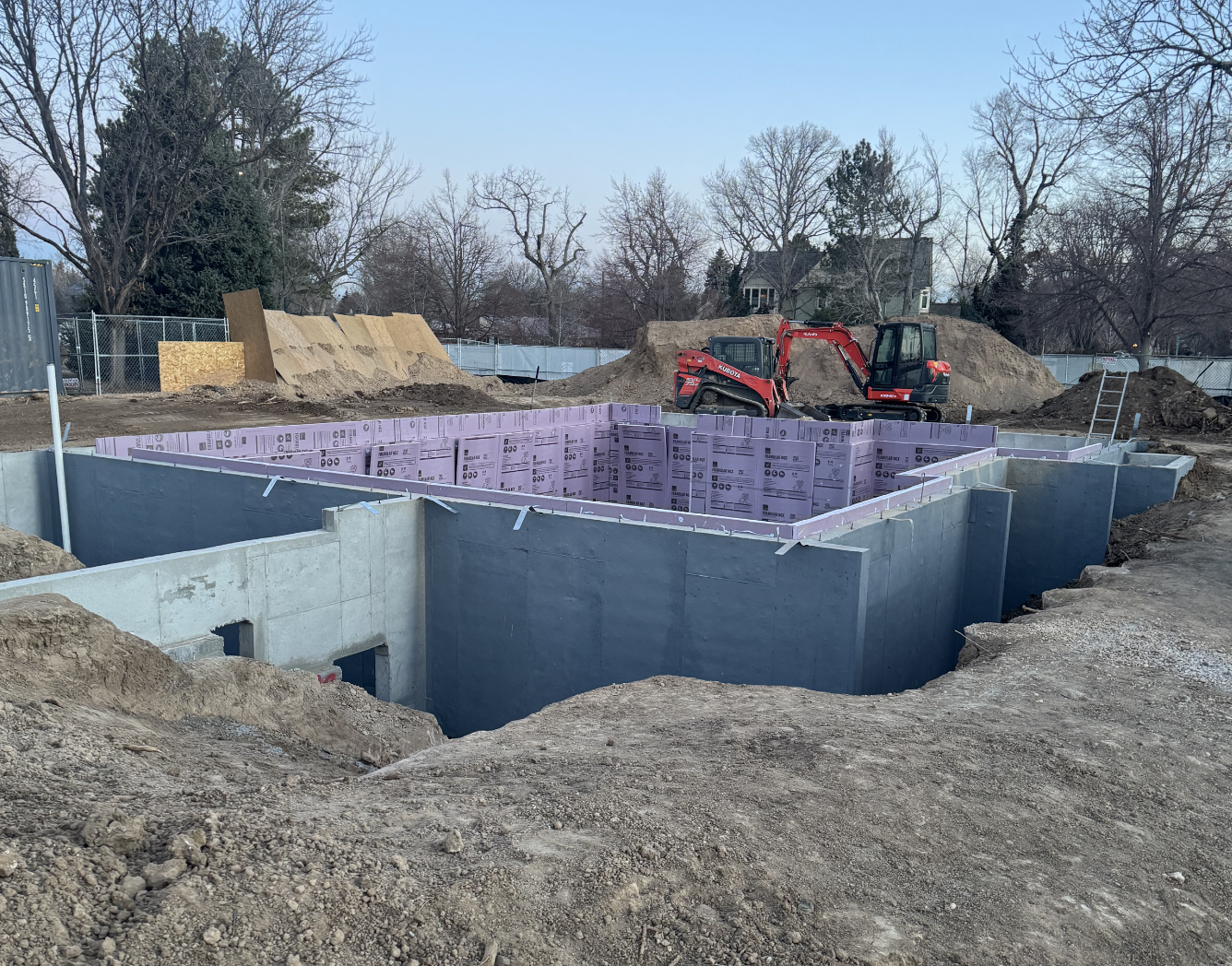 The Elizabeth Victorian-style home addition. Mid-project construction site with an unfinished building foundation, showing concrete walls