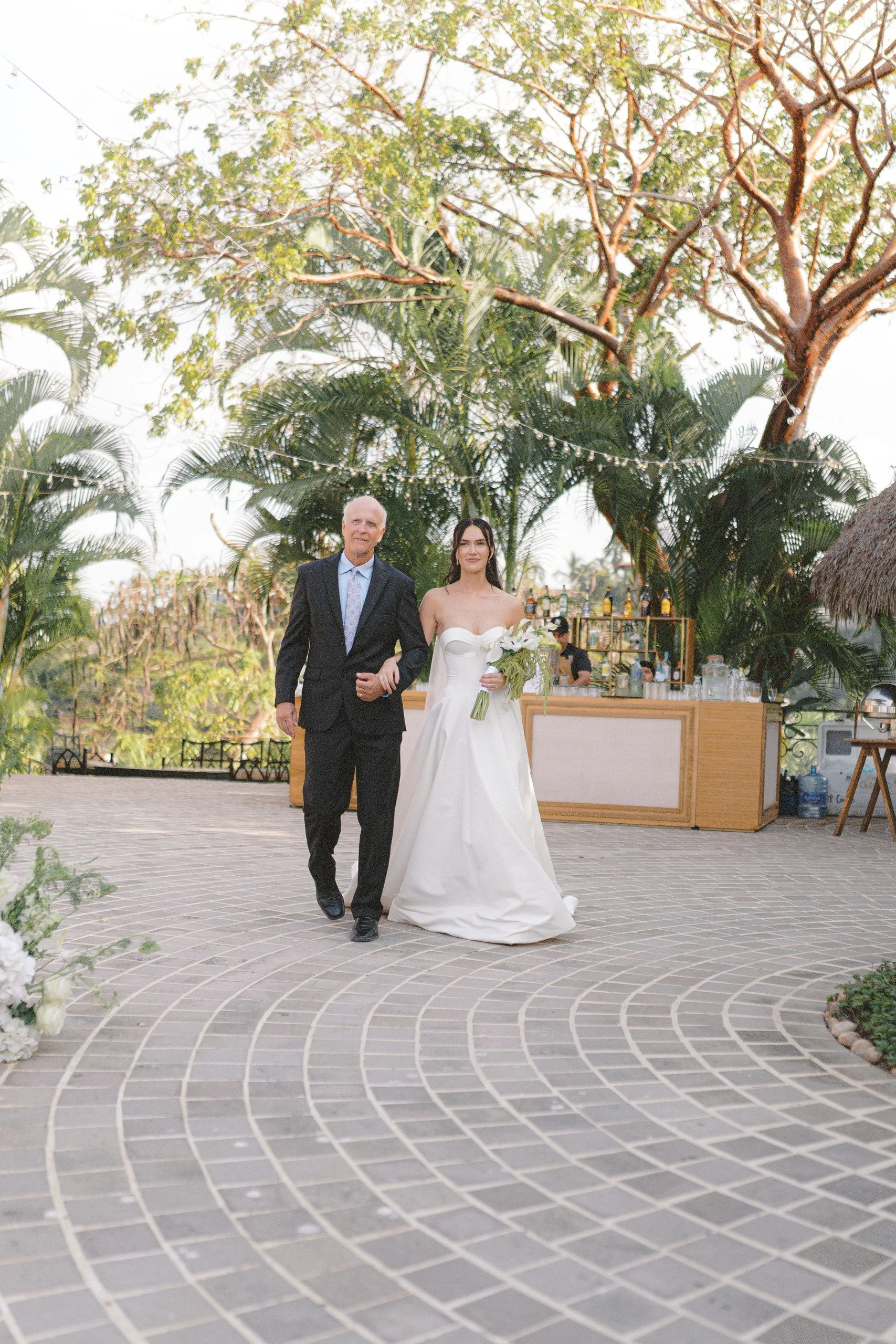 Bride walking with her father through the garden pathway before the ceremony at Gran Villa, Sayulita