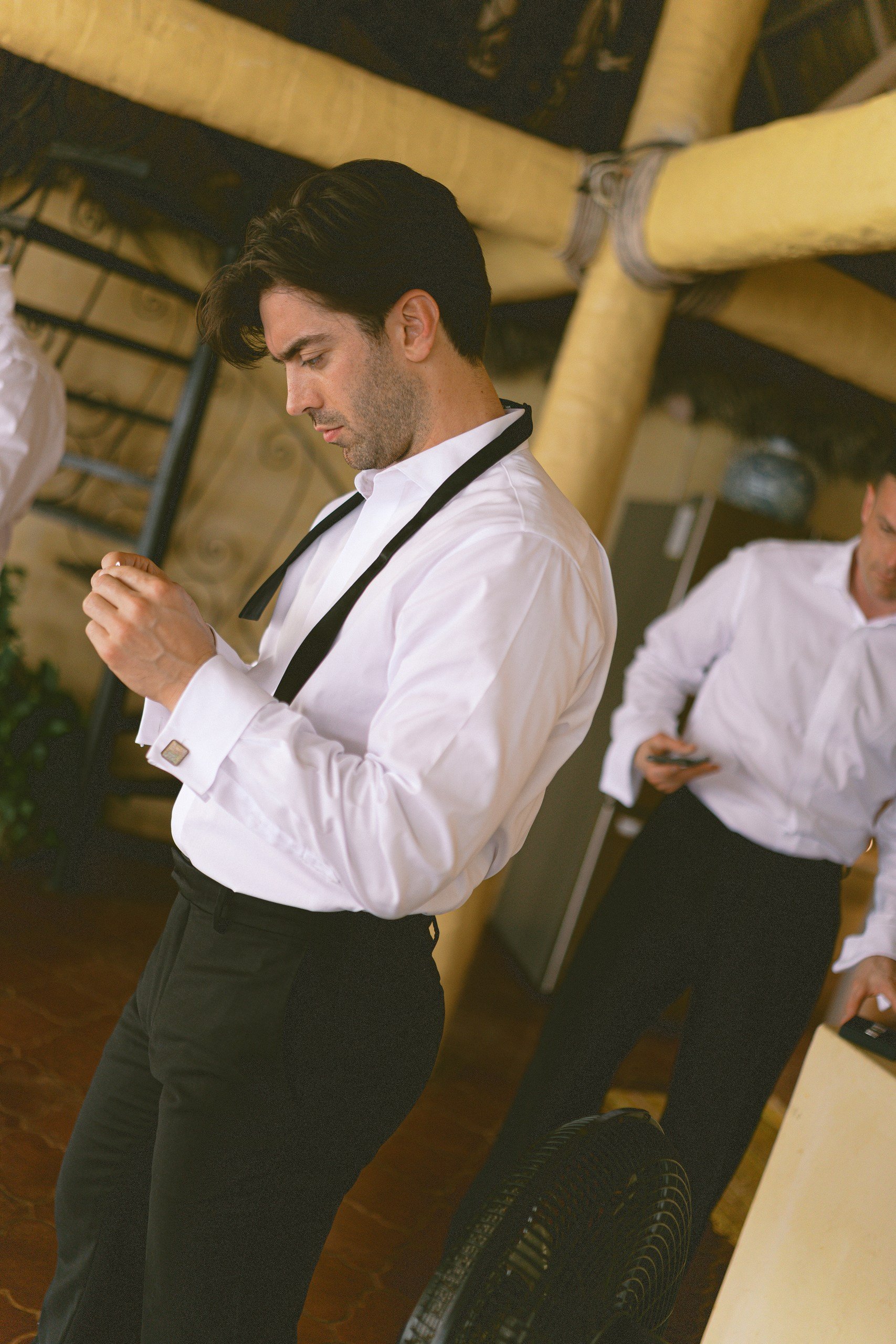 Groom putting on suspenders while getting ready for the wedding at Gran Villa, Sayulita