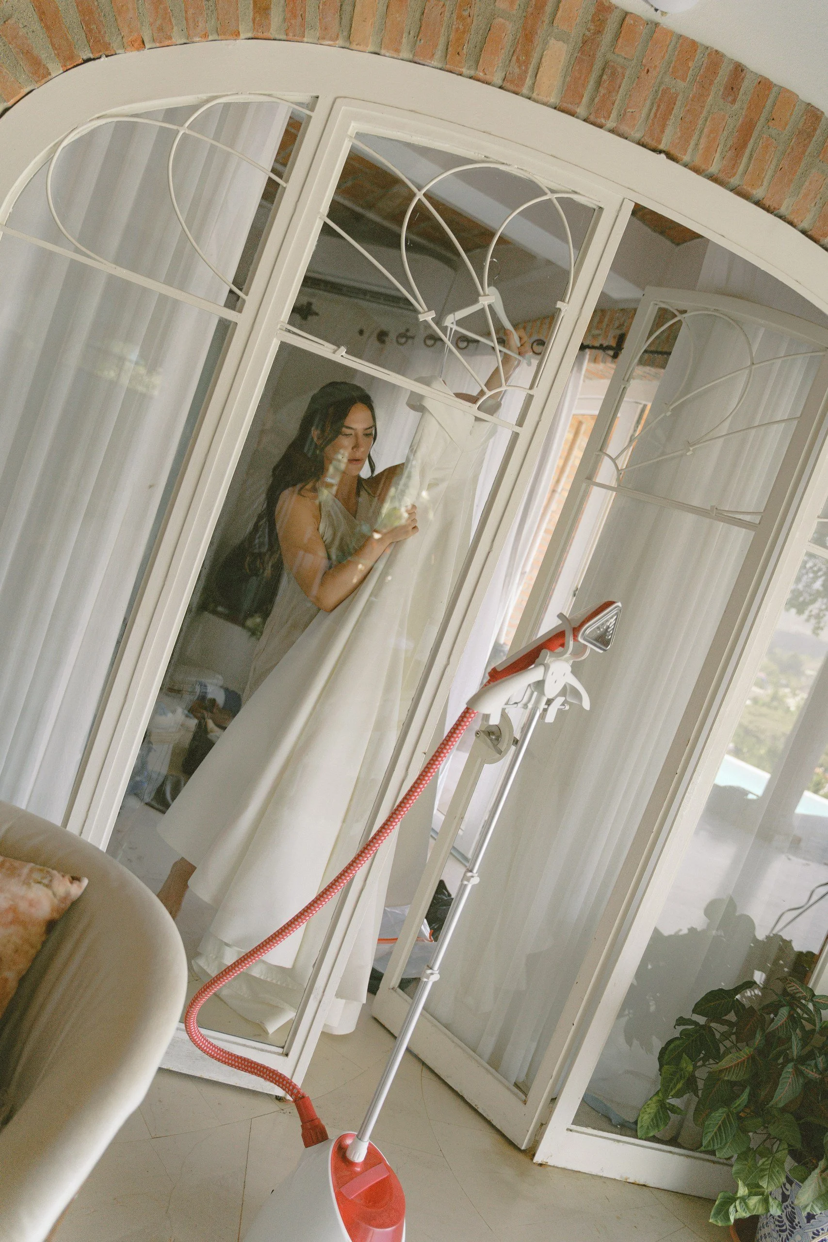 Bride's wedding dress hanging by a window before the ceremony at Gran Villa, Sayulita