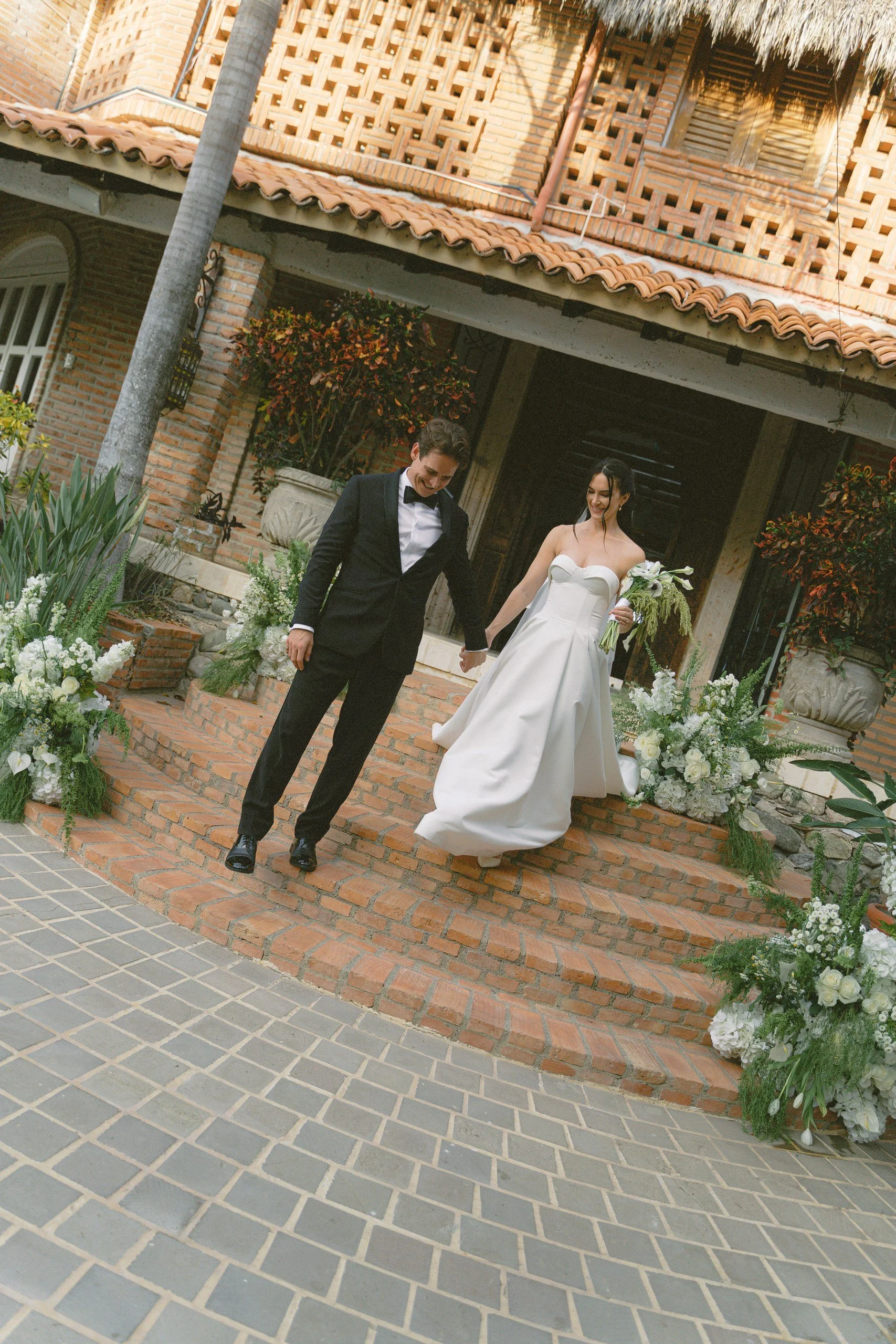 Newlyweds walking through the tiled courtyard entrance at Gran Villa, Sayulita
