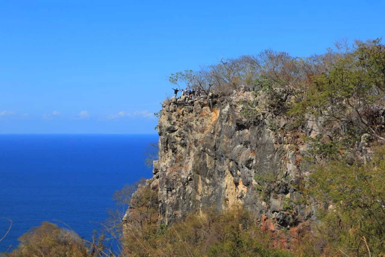 Hikers on a rocky cliffside trail overlooking the ocean near Sayulita
