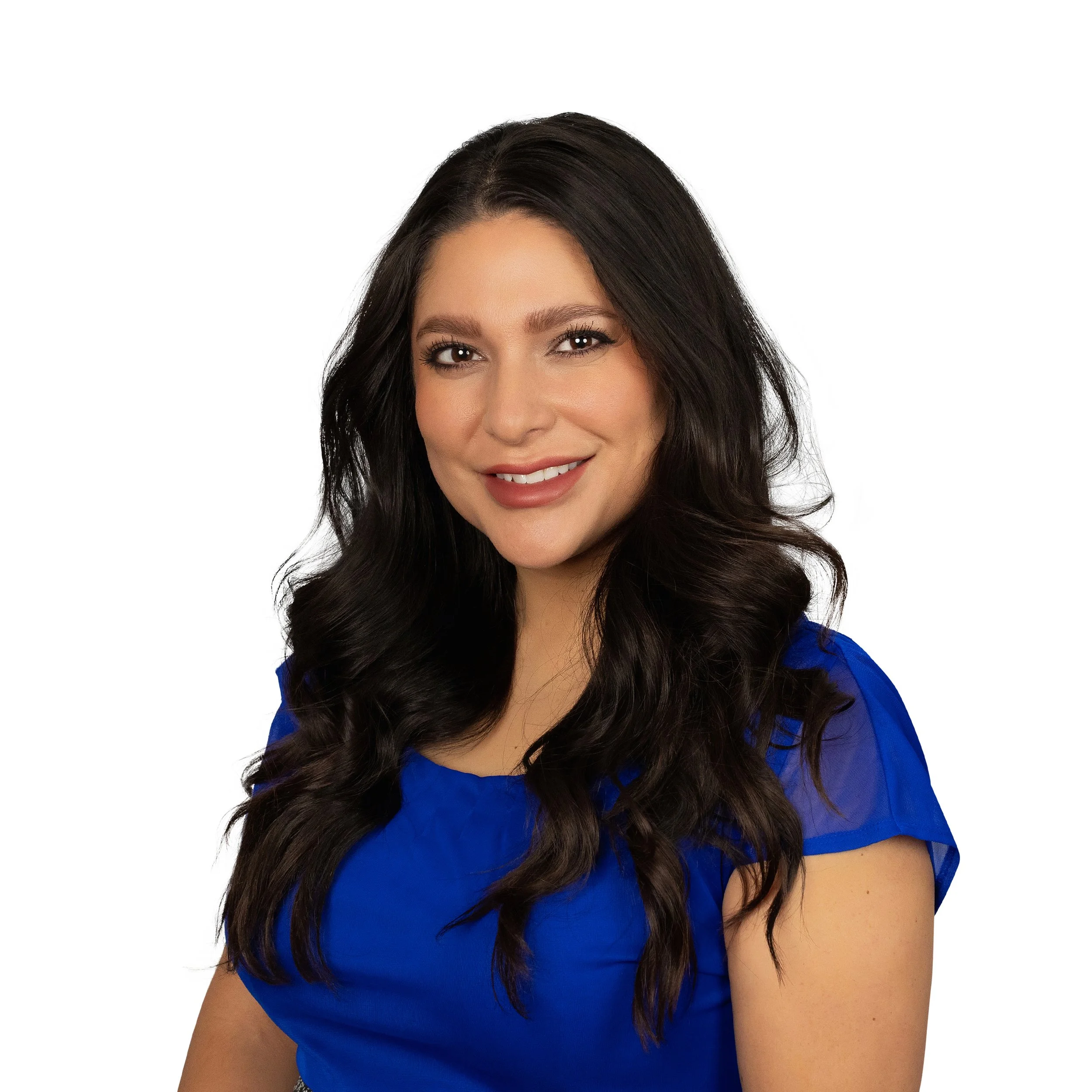 A woman with long wavy dark hair, wearing a blue top, smiling against a white background.