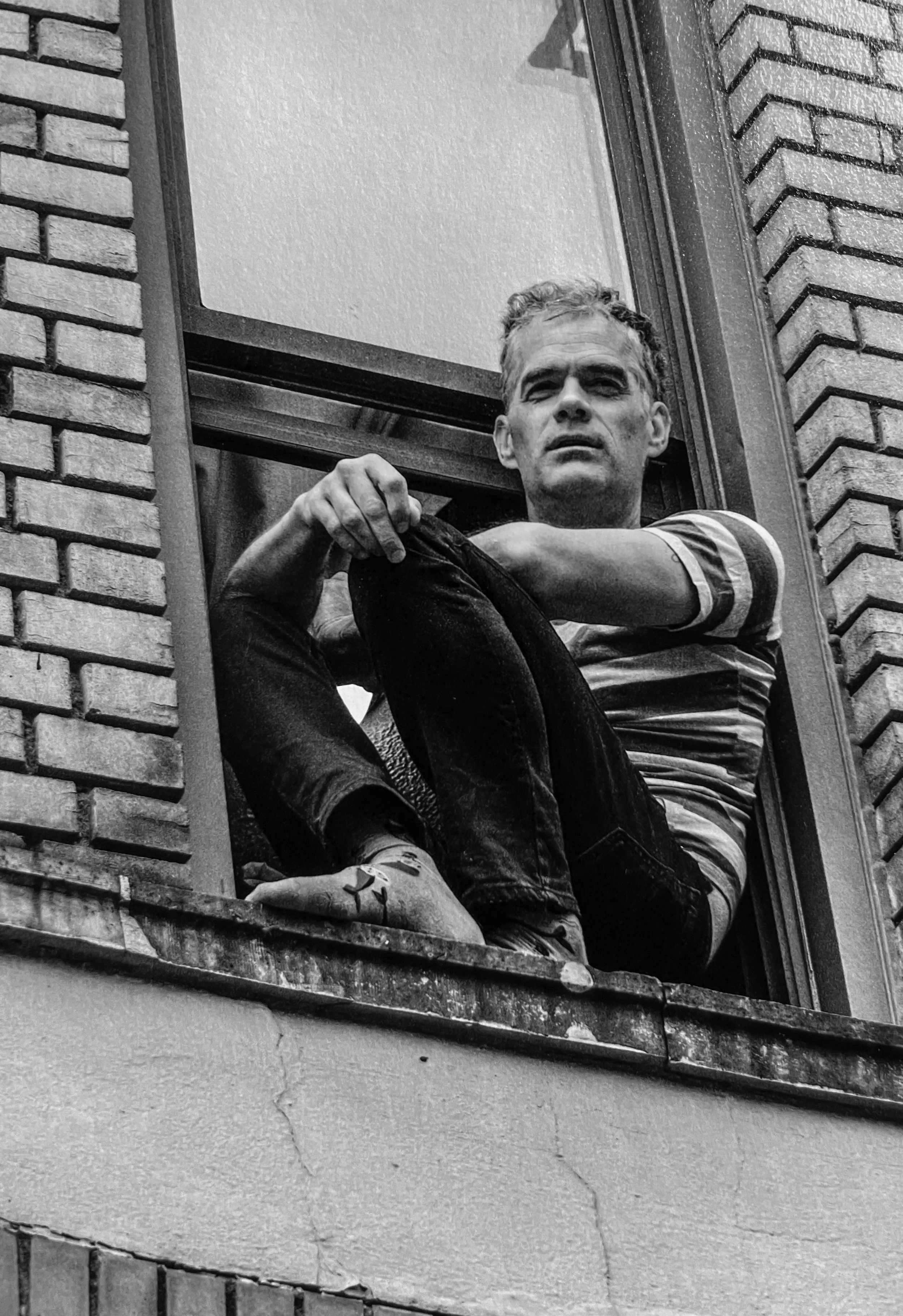 black and white photo of a man in a windowsill looking outside