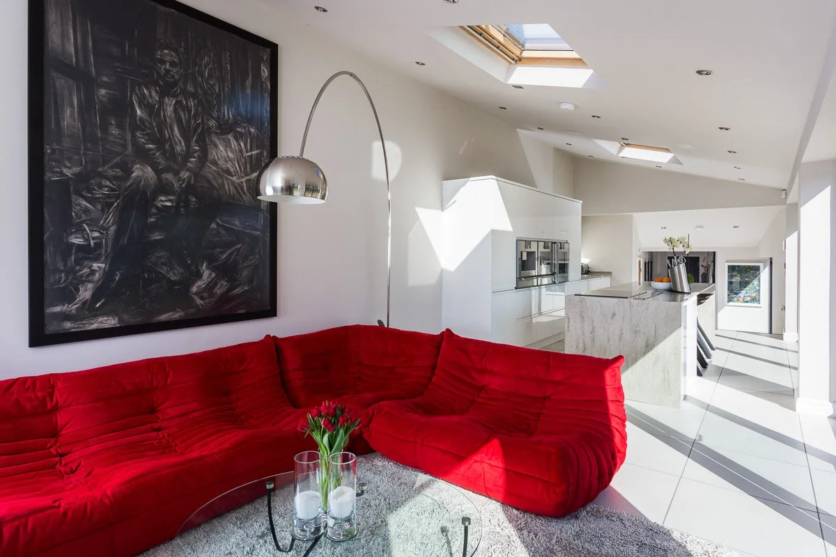 large kitchen/family room with sky lights, white walls, large red corner sofa 