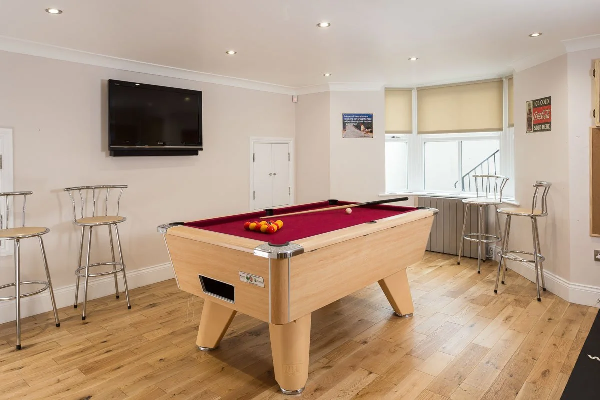 games room with wooden flooring, tall stools, pool table with red felt