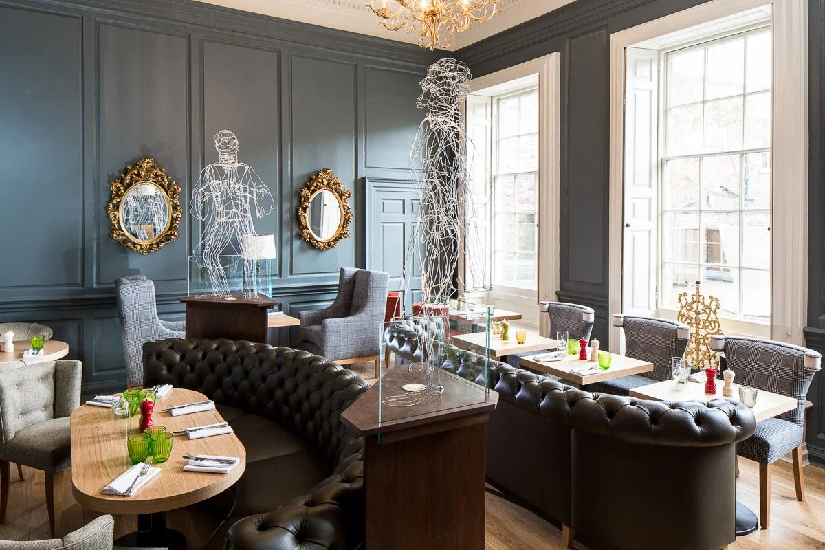 hotel restaurant area with high ceilings, pale blue panelled wall and deep leather bench seats