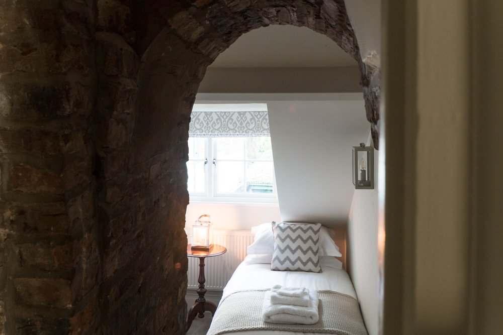  glimpse of a single bed under an original arched brick wall 