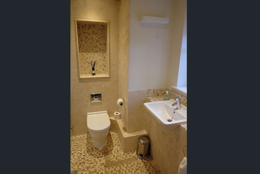  dark portrait image of beige tiled bathroom  