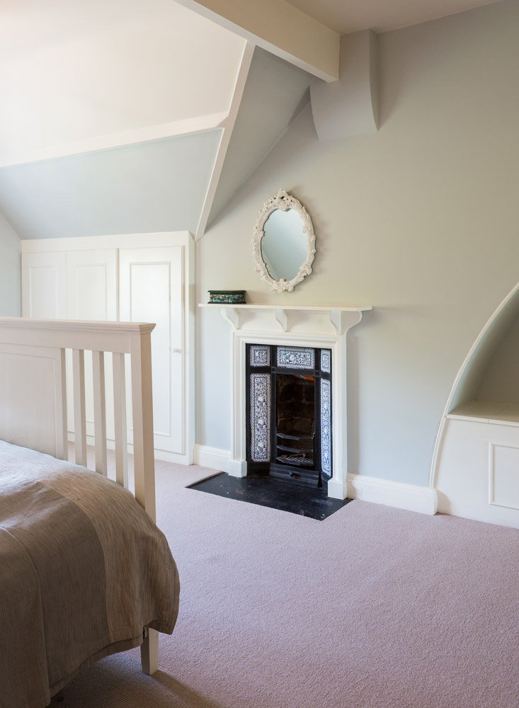  detail of traditional fireplace with end of bed out of focus, sage green walls 