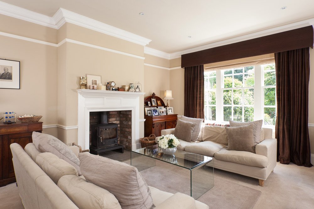  high ceiling living room with cream walls, cream sofas and log burner  