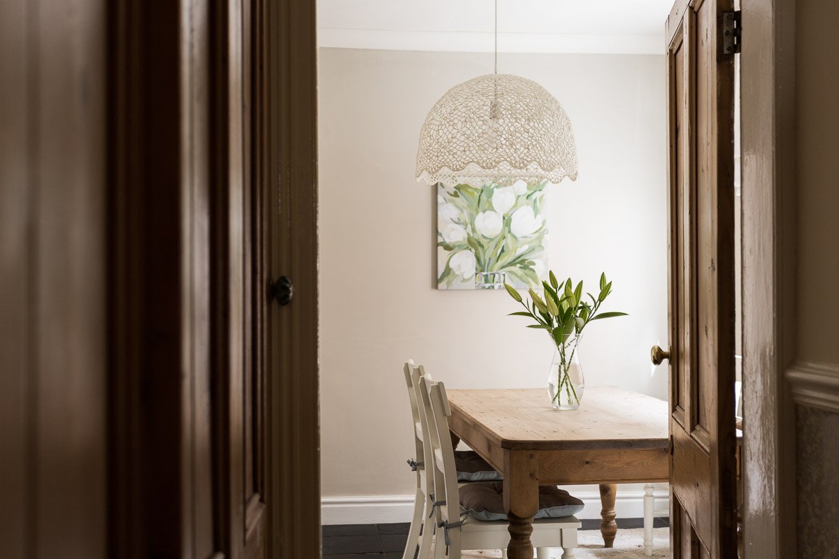  glimpse through door at softly lit farmhouse style dining room with wooden dining table with flowers 