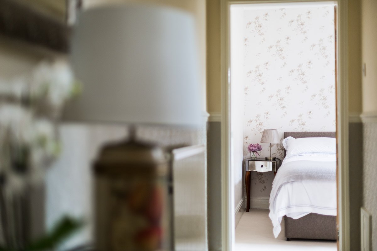  detail of bedside table in distance taken from hallway, lamp out of focus in foreground  