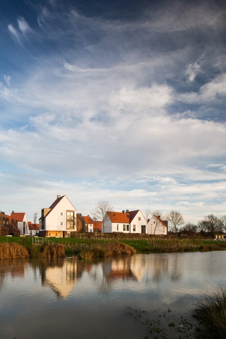   image across a pond looking at new build houses on sunny day  