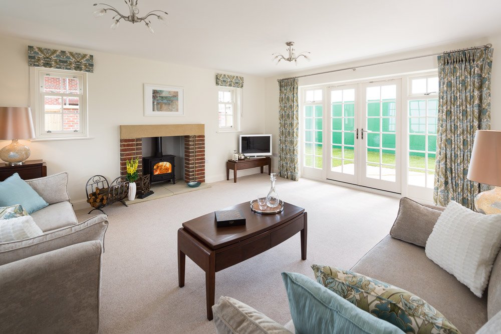  living room with cream carpets, grey sofas, coffee table, log burner in brick surround fireplace  