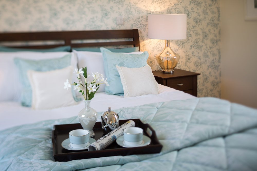  detail of breakfast tray set up on bed with blue bedsheets 