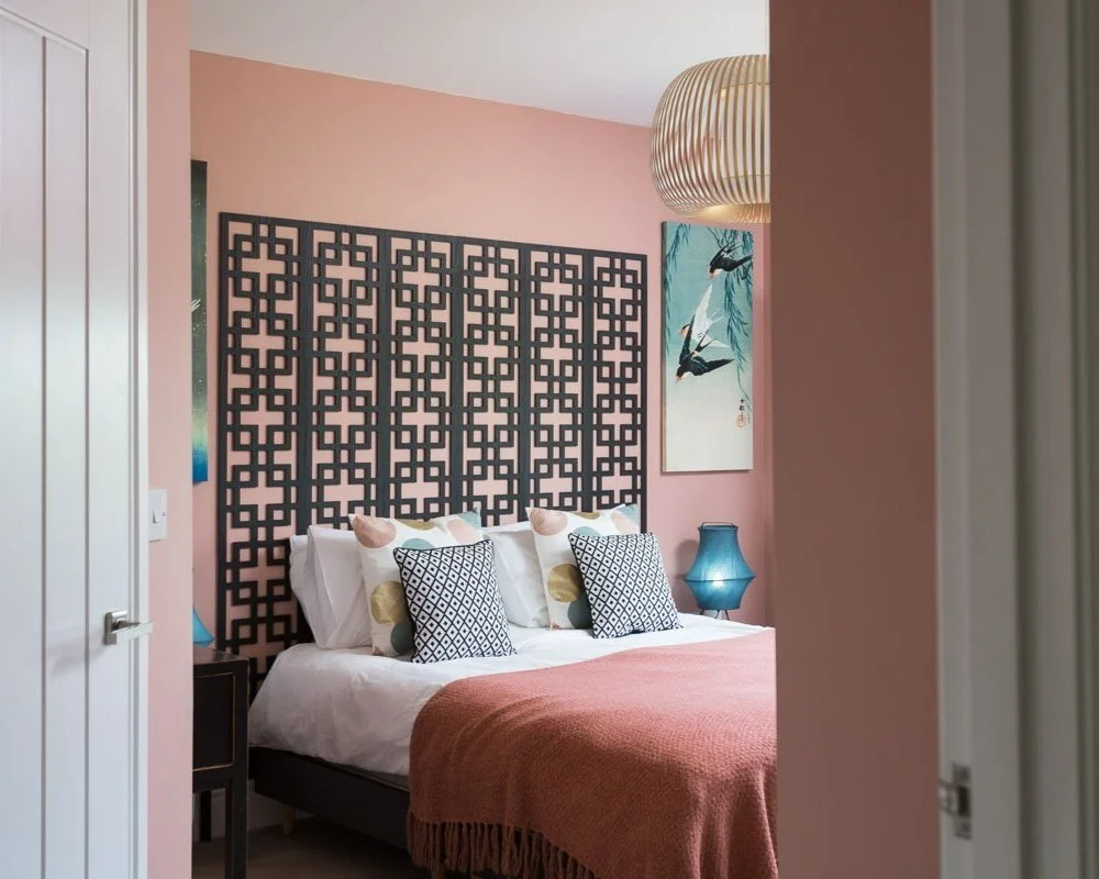 glimpse through bedroom door into pink bedroom with art deco headboard