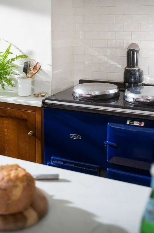 detail shot of glossy blue aga oven looking over white worktop with loaf of bread