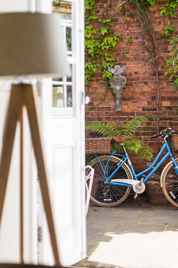 portrait shallow depth of field image through door of bike in courtyard and out of focus lamp in foreground 