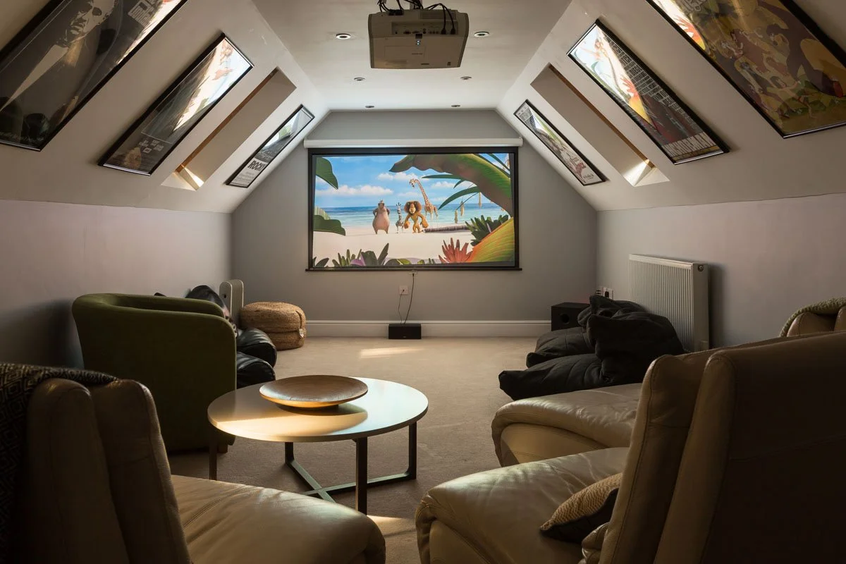 lofted ceiling cinema room with art prints on wall and leather arm chairs