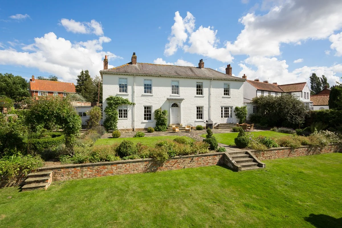 large white Georgian house with tiered manicured lawn