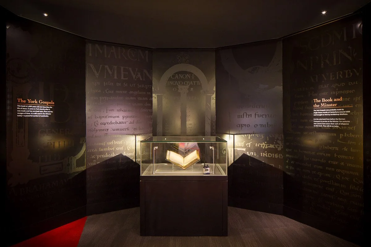 dimly lit exhibition about York minster with book in glass case