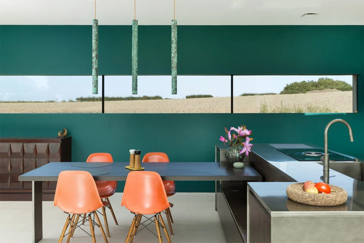 modern kitchen diner with panoramic letter box window and wood panelled wall, dark dining table and kitchen units with forest green wall