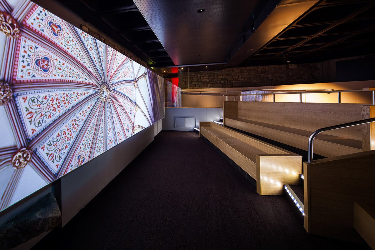 dark cinema room with bench seating and large projection screen in a museum