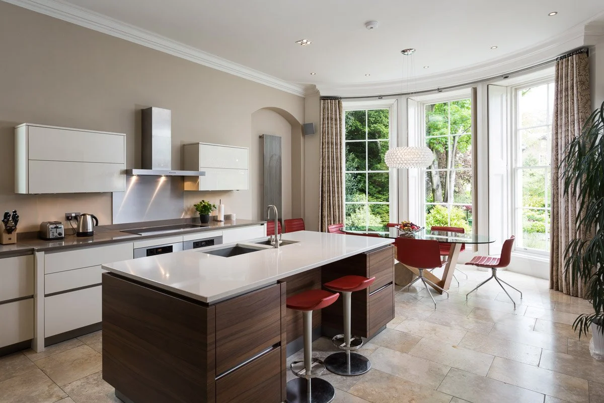 large high ceiling kitchen / breakfast room with beige walls an tile flooring, large bay window, dark wooden kitchen units, white counter tops