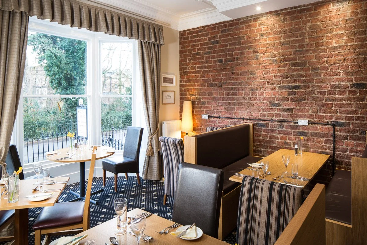 hotel restaurant area with high ceilings and brick wall