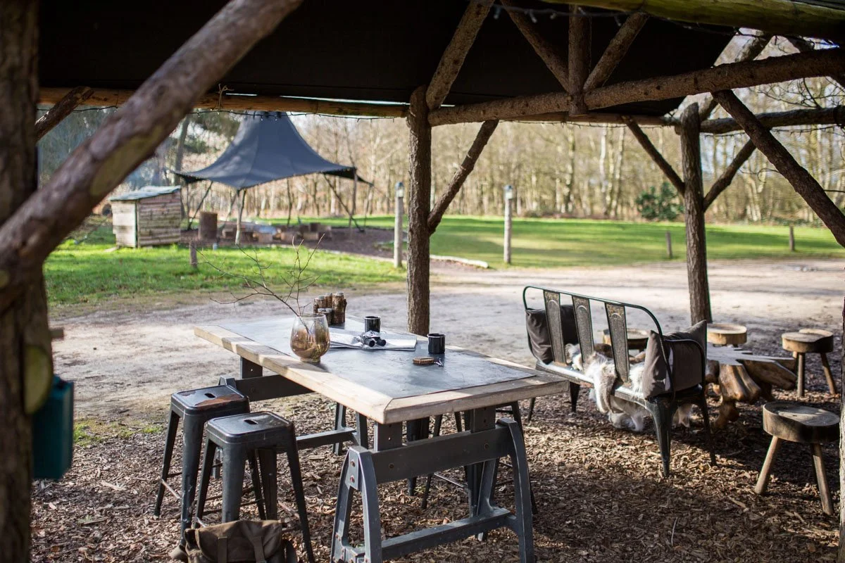 outdoor seating area under canvas cover with metal stools and tables