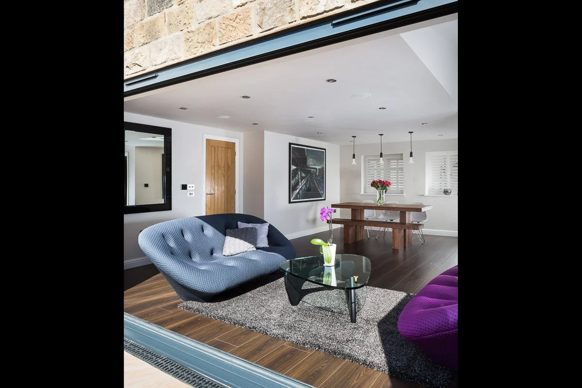 portrait image looking through bifold doors at dining/family are, wooden flooring, wooden dining table