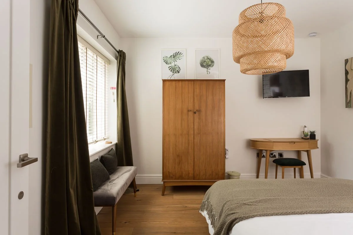 one point perspective of bedroom with wooden flooring, rattan light shade, and large window on left wall