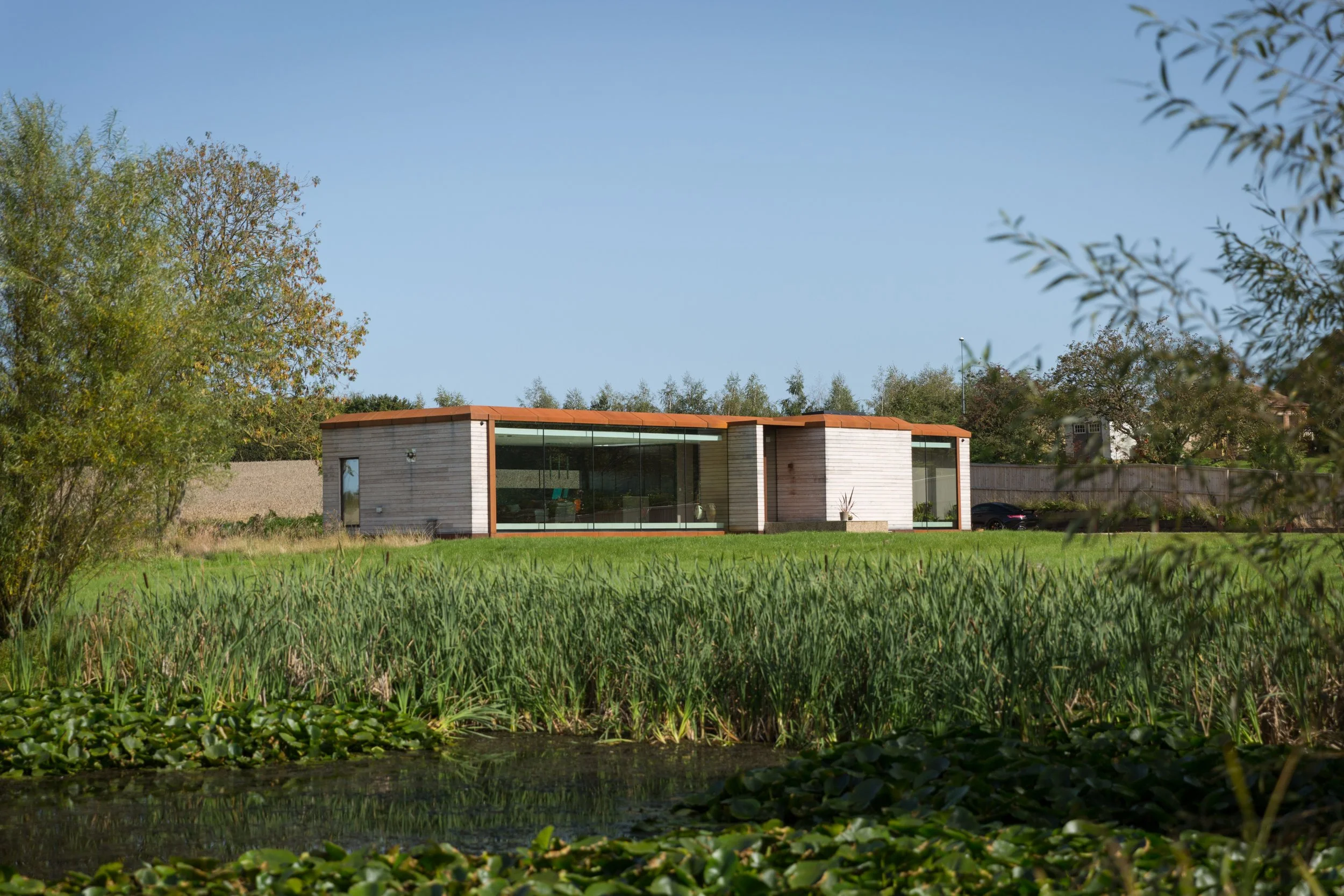 eco home with glass front from across a pond 