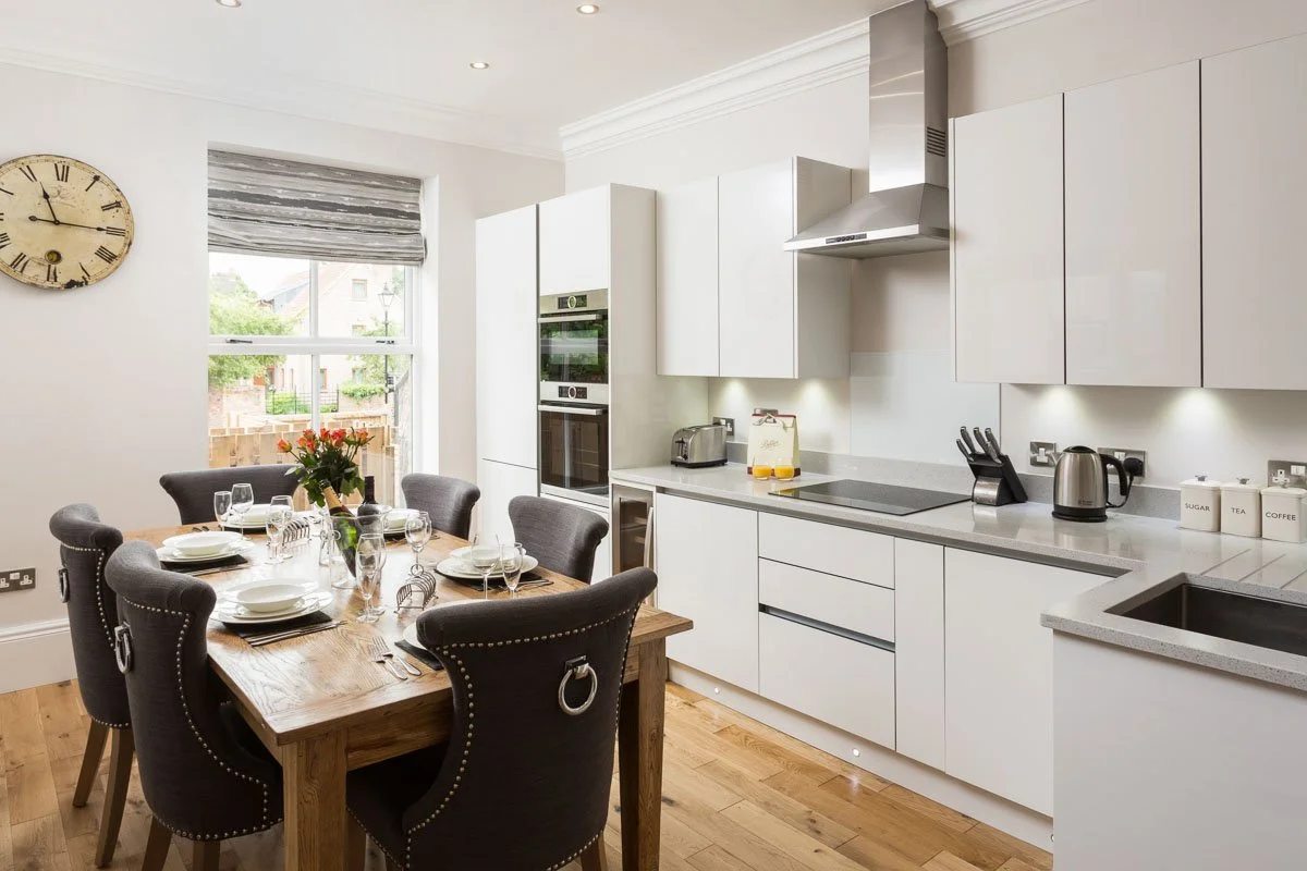kitchen diner with wooden flooring, white units, grey countertops, wooden dining table with dark grey chairs