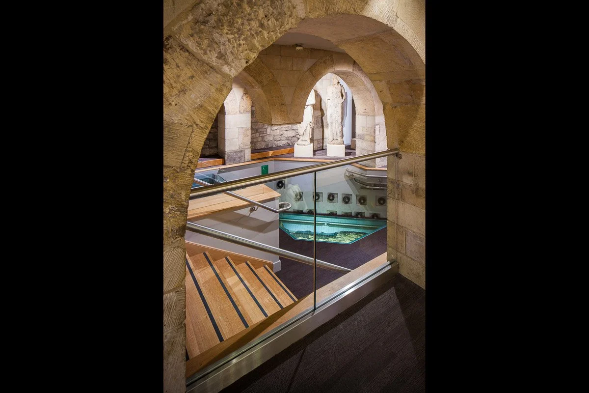 looking through stone archway downstairs towards museum exhibitions about building york minster 