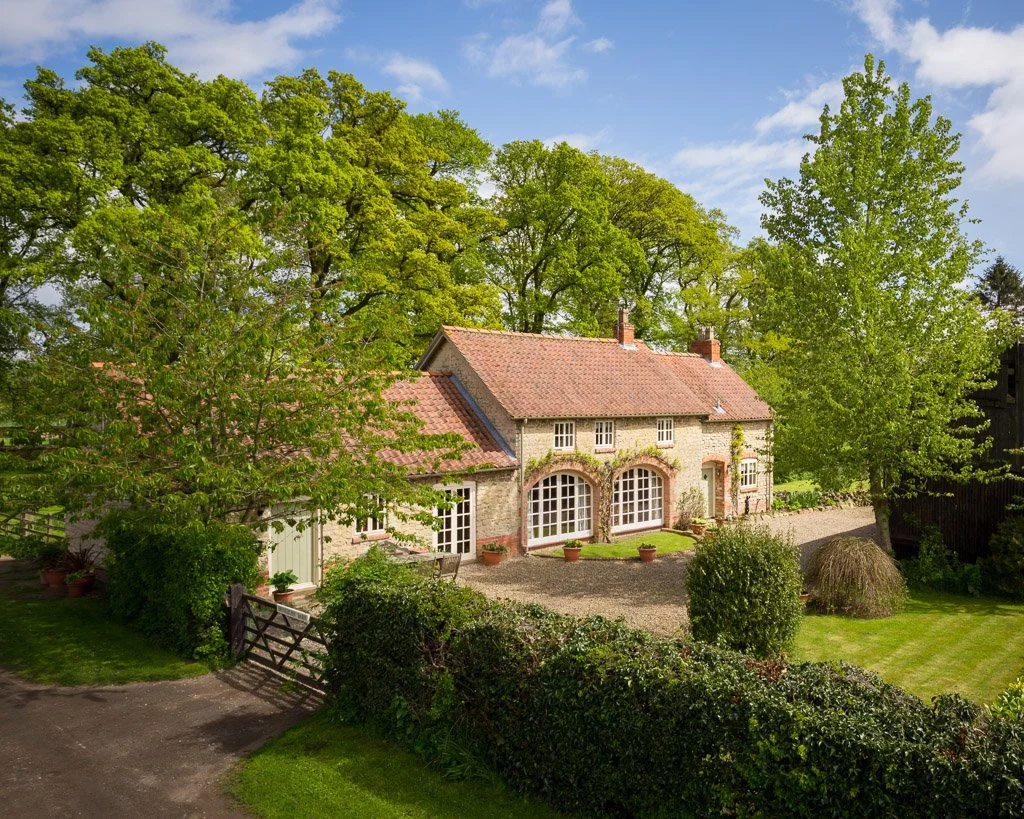 cottage surrounded by trees, gravel driveway